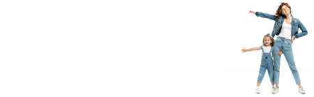 daughter and mother in denim outfits with outstretched hands isolated on white, panoramic shotの写真素材