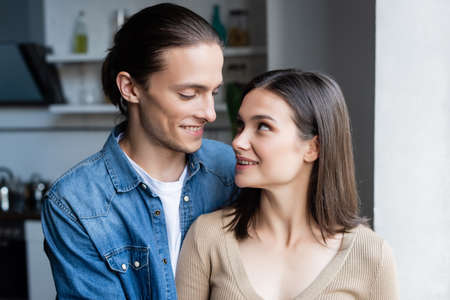 young couple looking at each other while standing together at home