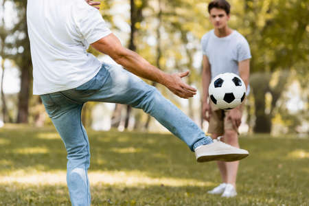 selective focus of father kicking football near teenager sonの写真素材