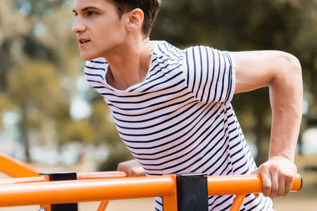 strong teenager boy exercising on horizontal bars