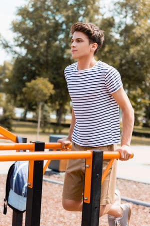 sportive teenager boy exercising on horizontal bars