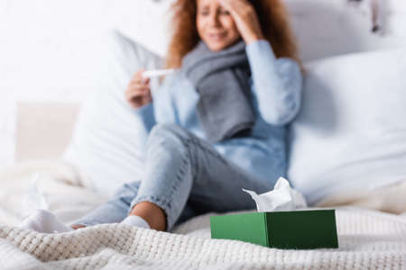 Selective focus of box with napkins near ill woman on bed