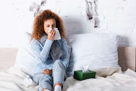 Selective focus of sick woman holding napkin on bedの写真素材