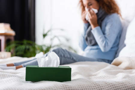 Selective focus of box with napkins near sick woman on bedの写真素材