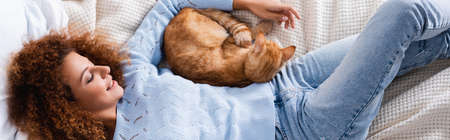 Horizontal crop of woman lying near cat on bedの写真素材