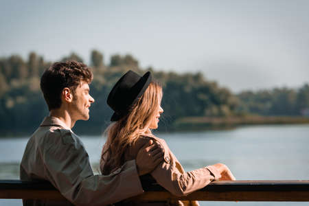 blonde woman in hat and man looking away outside