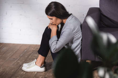 Selective focus of woman sitting on floor near couch