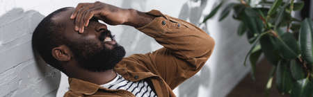 Horizontal crop of african american man touching eyes