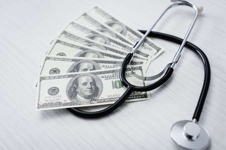Selective focus of stethoscope and dollar banknotes on white tableの写真素材