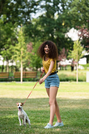 Selective focus of young woman looking away and keeping dog on leashの写真素材