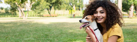 Panoramic shot of young woman looking at camera and holding dogの写真素材