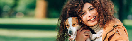 Panoramic shot of woman hugging jack russell terrier outdoorsの写真素材