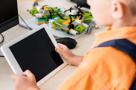 Cropped view of schoolboy holding digital tablet in stem schoolの写真素材