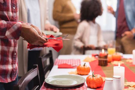 Selective focus of african american woman holding cutlery near decorations on table during thanksgiving celebrationの写真素材