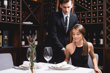 Selective focus of man in suit standing near elegant girlfriend in restaurant
