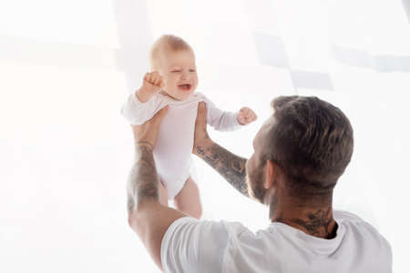 back view of young father holding excited baby boy in outstretched handsの写真素材