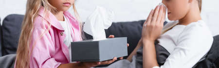 Panoramic shot of kid holding box with napkins near sick motherの写真素材