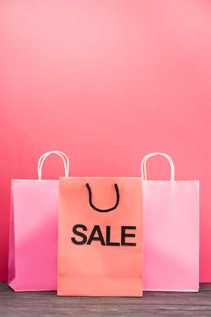 shopping bag with sale lettering near paper packets on pink, black friday conceptの写真素材