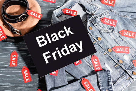 top view of placard with black friday lettering on denim jacket near beret and beltの写真素材