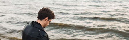 Panoramic shot of man in leather jacket standing near seaの写真素材