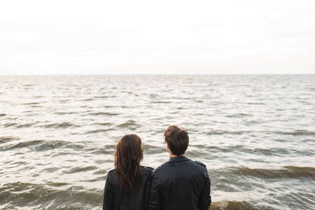 Back view of couple in black leather jackets looking at sea
