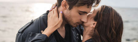 Horizontal crop of woman touching neck of boyfriend beside seaの写真素材