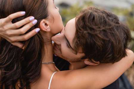 Selective focus of man kissing neck of young girlfriend outdoorsの写真素材