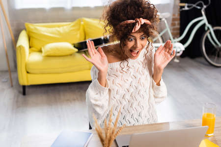 selective focus of excited woman laughing and looking at laptop