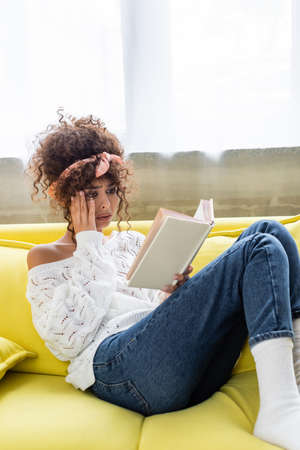 sad young woman reading book in living room
