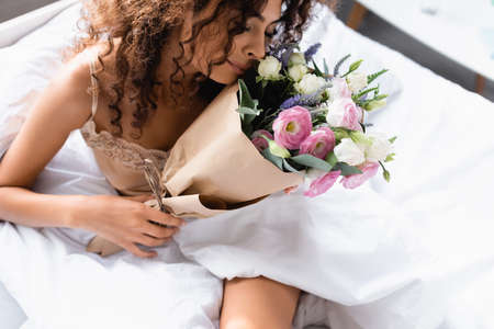 young woman smelling flowers in paper wrap at homeの写真素材
