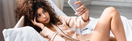 panoramic crop of young woman taking selfie in bedroomの写真素材