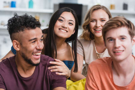 selective focus of excited multicultural friends watching film during party