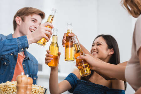 selective focus of multiethnic friends clinking bottles of beer during partyの写真素材
