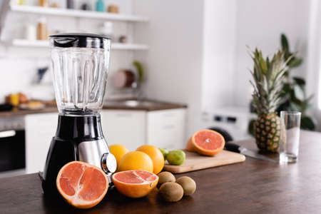 Selective focus of ripe fruits near blender on kitchen tableの写真素材