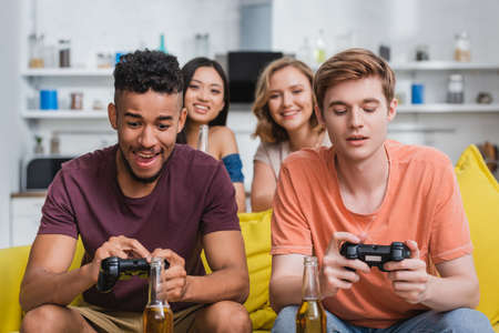 KYIV, UKRAINE - JULY 28, 2020: multicultural friends playing video game during party in kitchenのeditorial素材