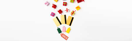 Panoramic orientation of price tag with sale lettering near credit cards and toy gifts on white...