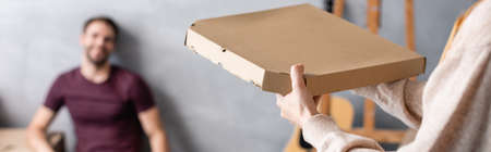 selective focus of woman holding carton pizza box near boyfriend, panoramic crop