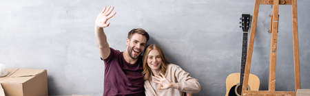panoramic concept of man and woman waving hands near acoustic guitar and boxの写真素材