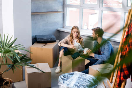 selective focus of young woman unpacking box with man, moving conceptの写真素材