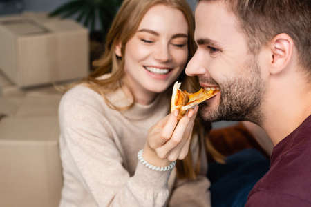 selective focus of woman feeding bearded man with pizzaの写真素材