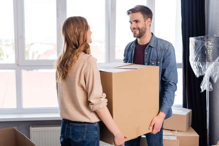 bearded man and woman holding carton box, moving concept