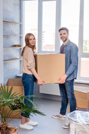 joyful man and woman holding carton box and looking at camera, moving concept