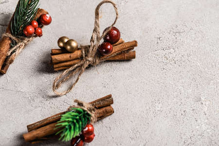 Cinnamon sticks with red beads on textured and gray background