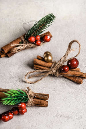 Cinnamon sticks with red beads on textured and gray background