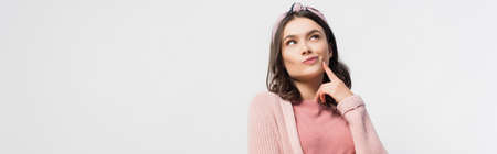 horizontal image of pensive woman in headband touching face and looking up isolated on white