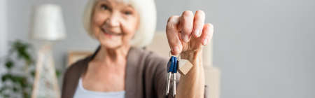 panoramic shot of blurred smiling senior woman holding keys, moving conceptの写真素材