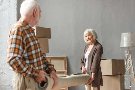 senior couple rolling carpet in new house, moving conceptの写真素材