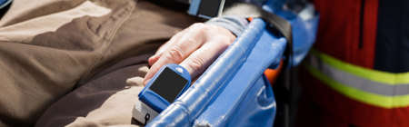 Website header of senior man with heart rate monitor lying on stretcher