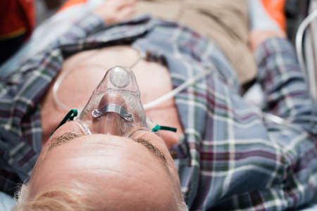 Selective focus of elderly man in oxygen mask lying in ambulance car