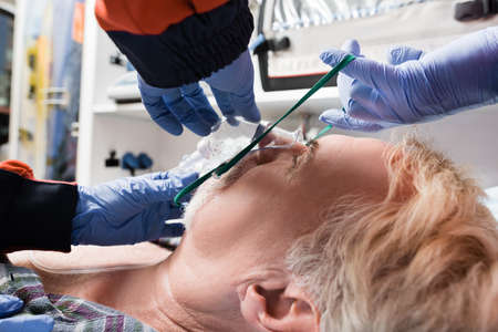Selective focus of paramedics in latex gloves wearing oxygen mask on patient in ambulance auto